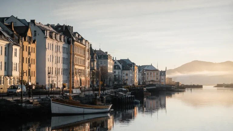 A quiet Scandinavian waterfront lined with pale, orderly buildings under soft morning light.